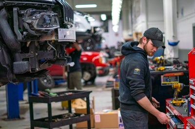 Karl Chevrolet technician working in the Ankeny service department with trucks on vehicle lifts
